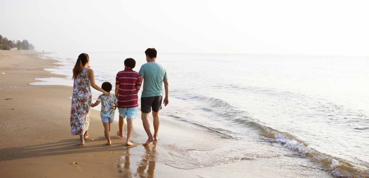 a group of people walking along a beach next to the ocean.